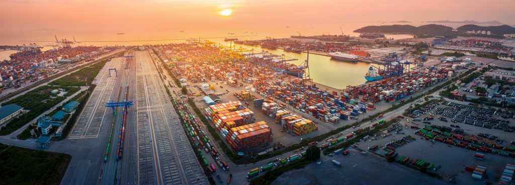 The International cargo container depot at sunset , multiple supply chain truck train and cargo ship working service shipping and transportation concept logistic and transport