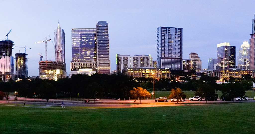 An image at dawn showing the Austin, Tx skyline and noticeably accentuated are numerous cranes.